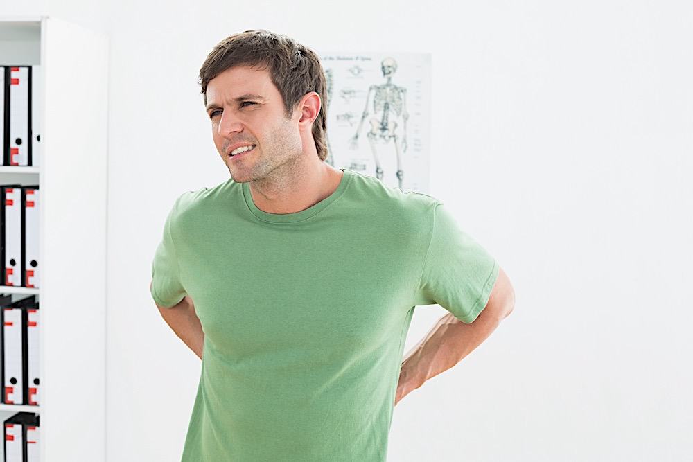 Portrait Of A Handsome Young Man With Back Pain Standing In The Medical Office
